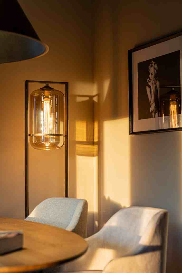 Deux chaises et un lampe design sur un mur beige avec un cadre photo