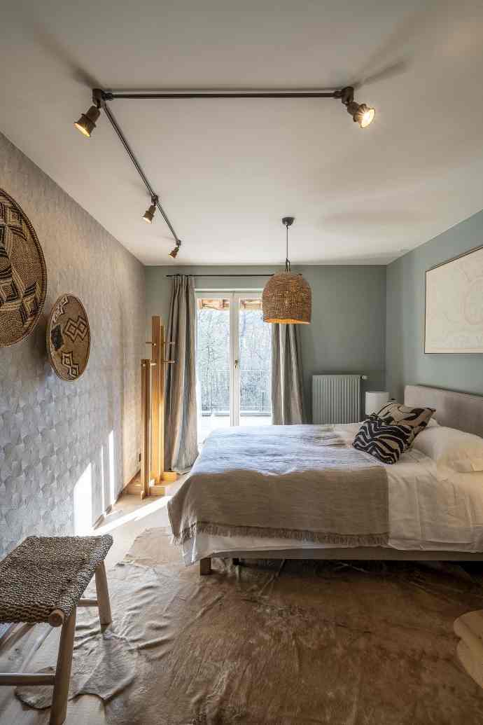Chambre cozy avec lit, éclairage sur rail, art mural africain et vue sur la nature