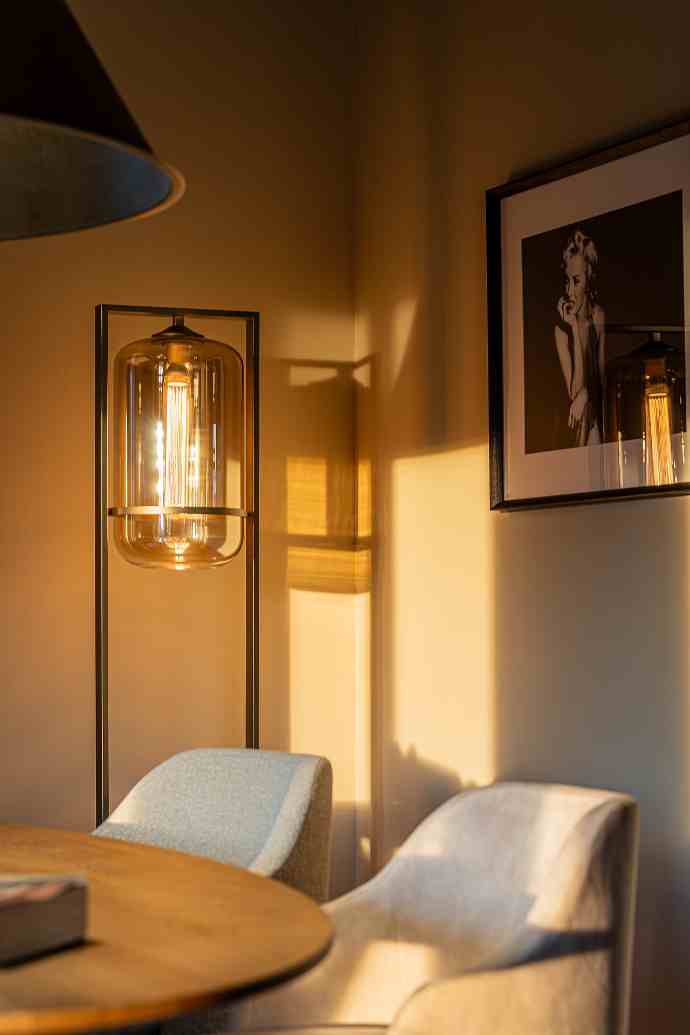 Ambiance cosy avec lumière tamisée, lampe design, cadre photo et mobilier moderne.