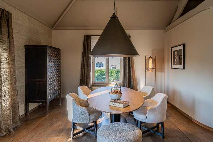 Salle à manger épurée avec grande table ronde, chaises en tissu et éclairage design