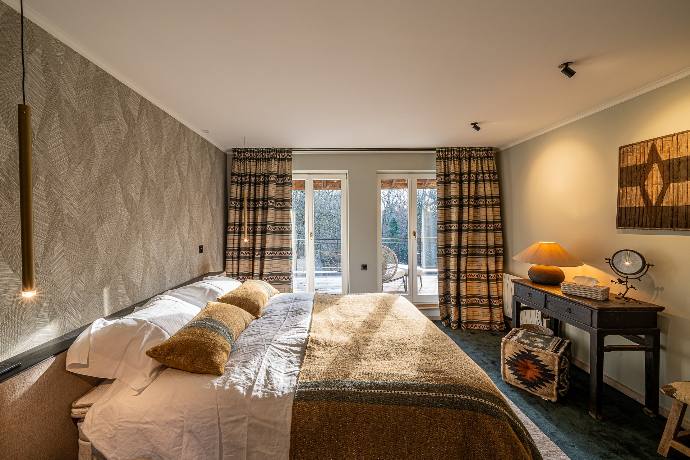 Chambre douillette avec lit, suspension moderne, déco murale et accès terrasse