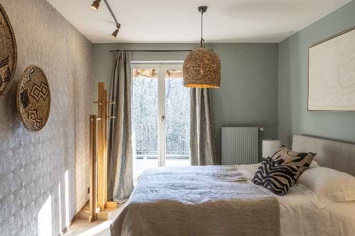 Chambre harmonieuse avec lit, décoration africaine, éclairage doux et vue sur les arbres