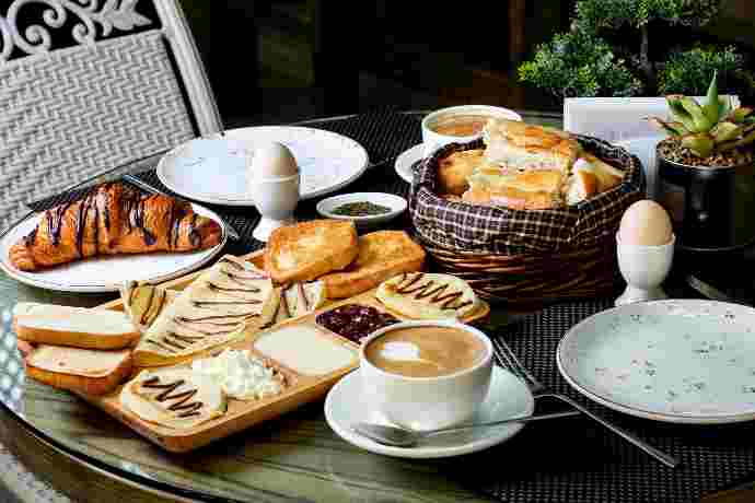 Petit-déjeuner gourmand avec croissants, toasts, œufs, café et plantes sur table
